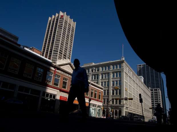 A man walks in downtown Calgary. While the U.S. economy performed better than expected in the final quarter of 2015, Canada's output likely slowed due to the ongoing drag from low oil prices and weak business investment.